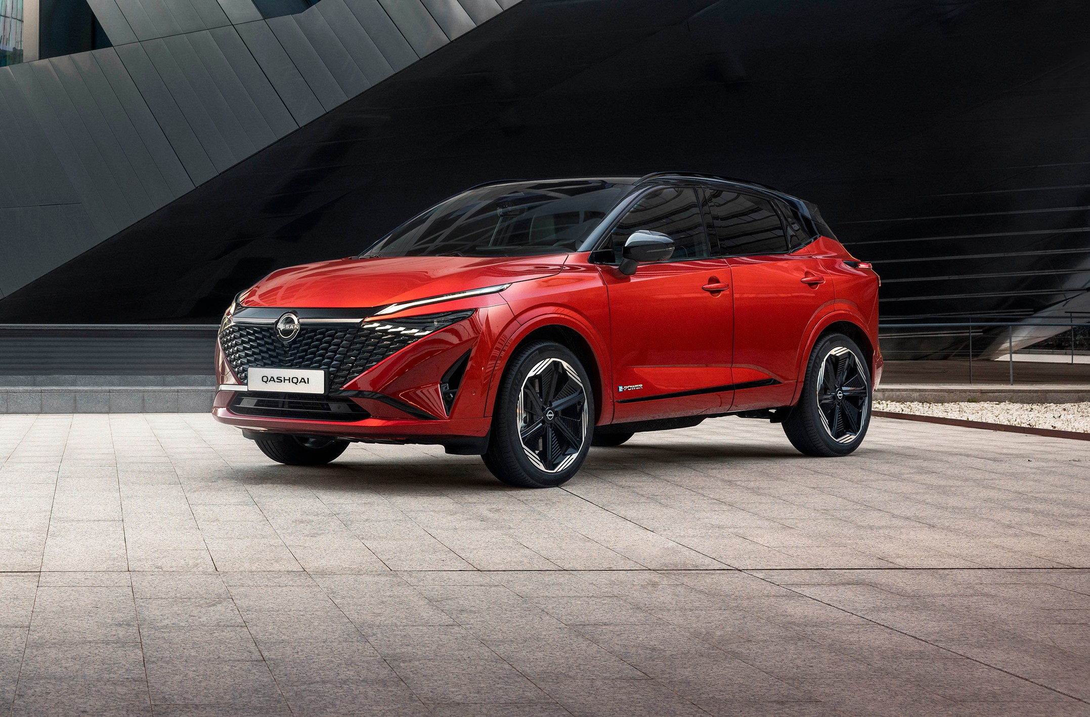 A red Nissan Qashqai parked in front of a building.