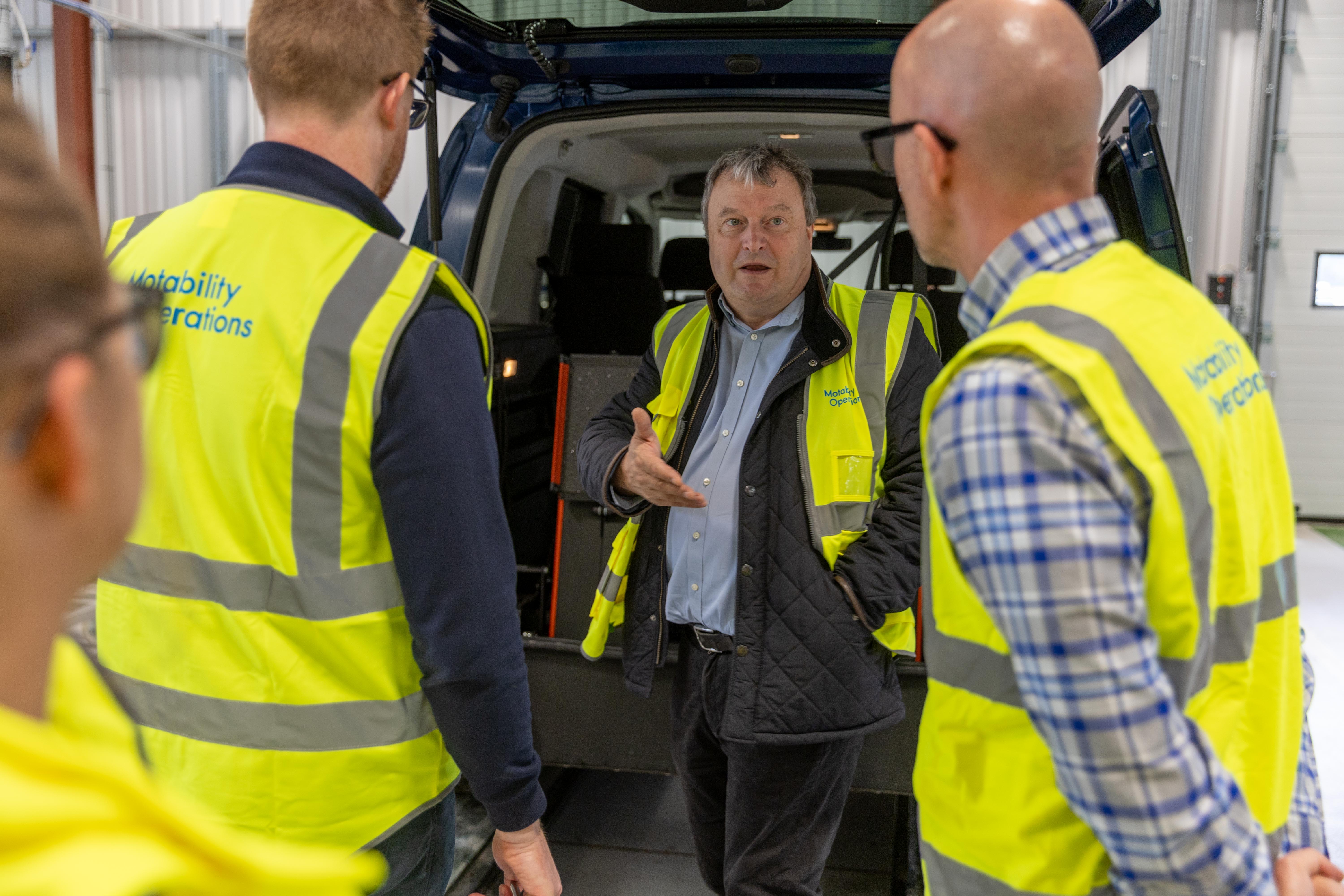 Andrew Miller, CEO of Motability, converses with team members.